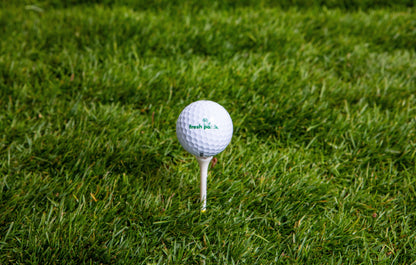Golf ball with 'fresh patch'  branding on a tee in the grass.