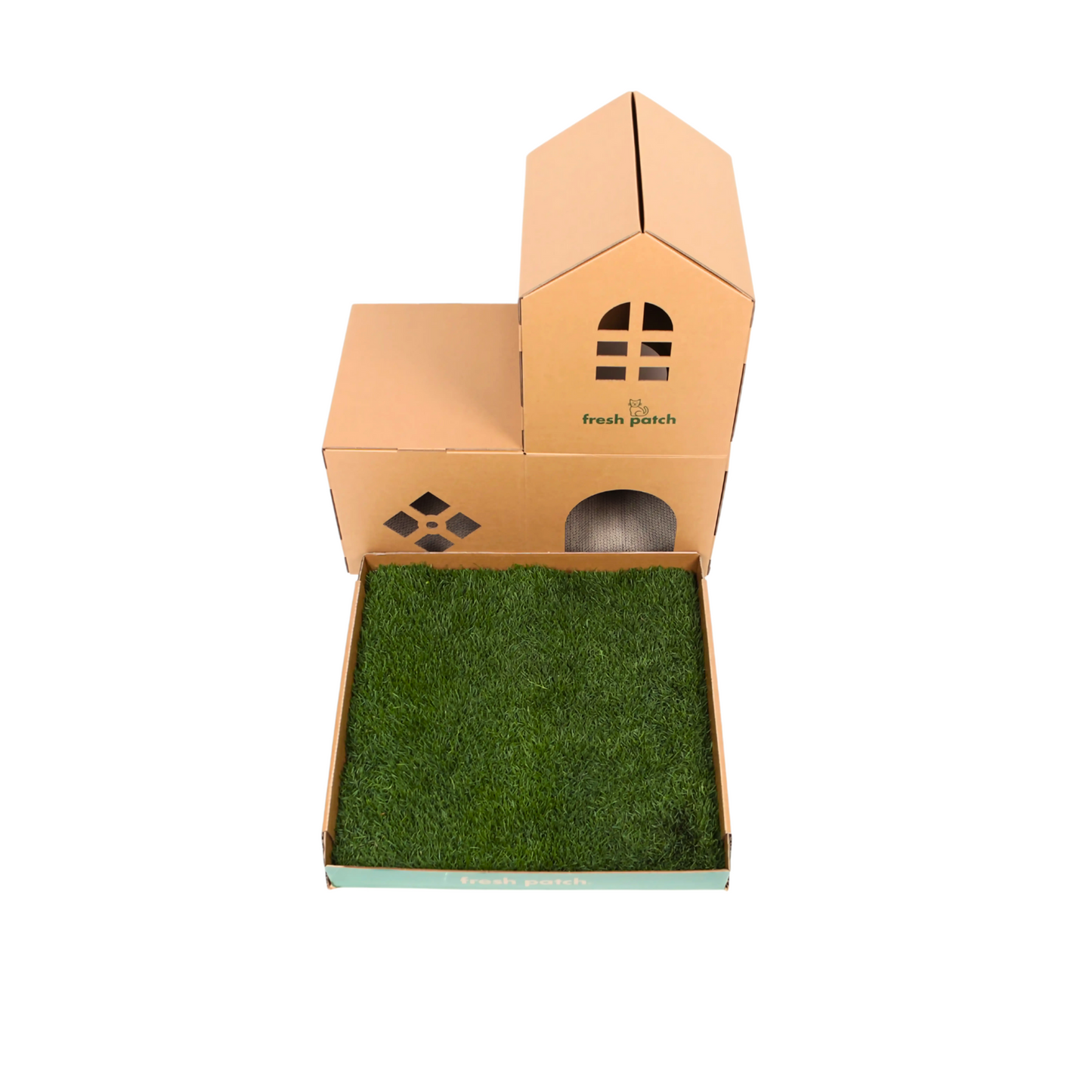 Cardboard cat house with green grass outside on a white background