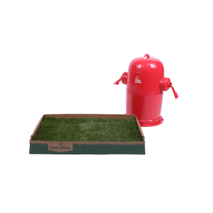 A red fire hydrant-shaped trash can next to a rectangular green real grass mat on a plain white background. The red toy has small red nozzles and a small white logo that appears to read 'Fresh Patch'.