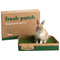Rabbit sitting inside a box of fresh patch with the packaging in the background.