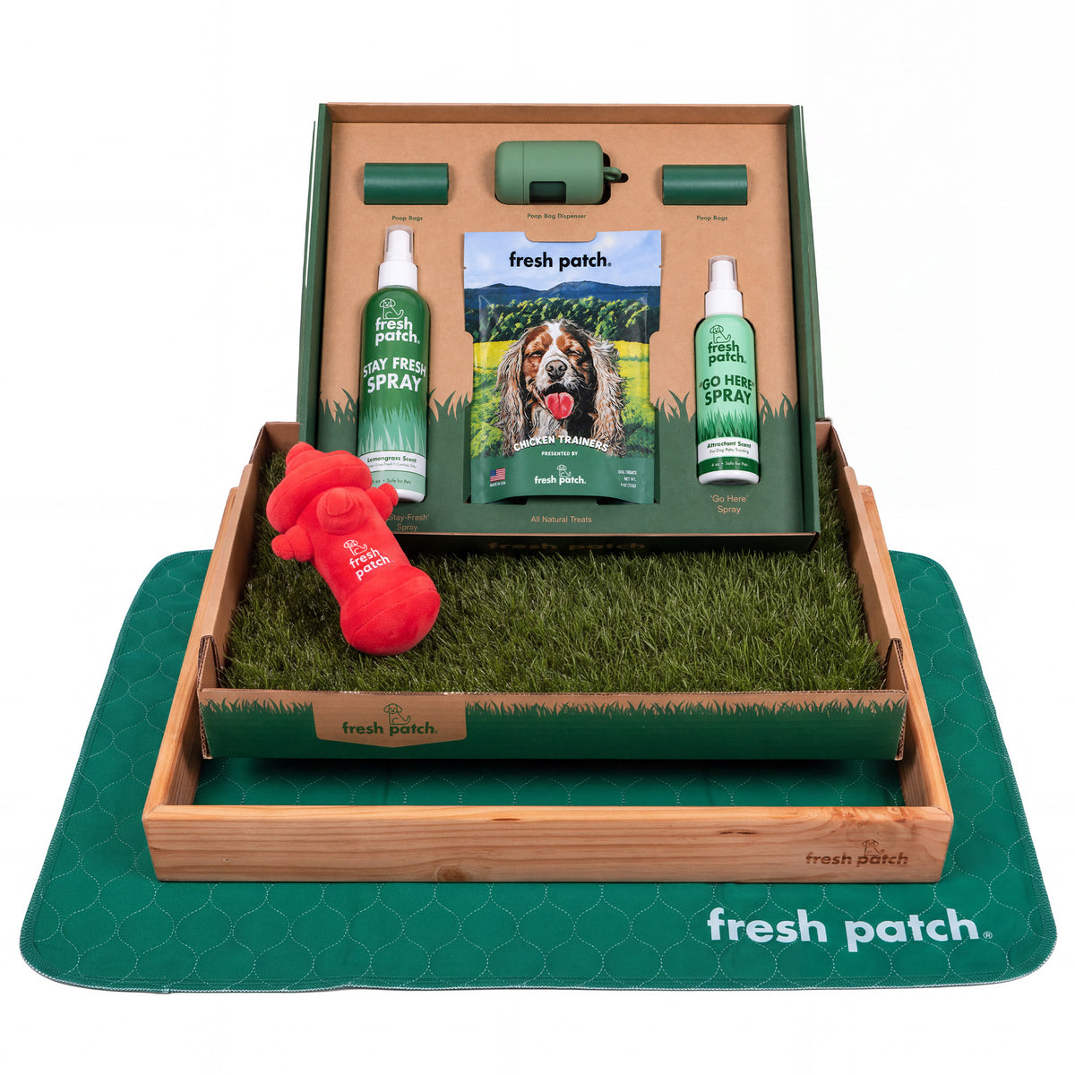 Fresh Patch potty training kit with a real grass tray in a wooden frame, a plush hydrant toy, two sprays, dog treats, poop bags and a green pad.